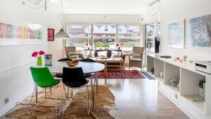 A modern dining area with a round table, two chairs, a rug, and a view of the outside through large windows.