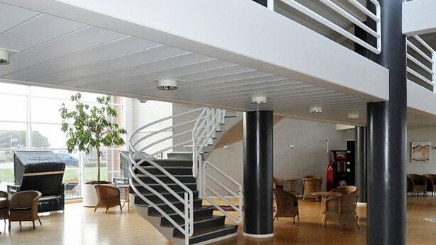 A spacious lobby with a spiral staircase, wooden flooring, and seating areas.
