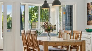 A dining area with a wooden table and chairs, a vase with flowers, and pendant lights. - "Ømund" - 600m to the fjord by Interhome (Holbæk)