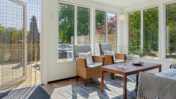 A sunlit room with large windows, wicker furniture, and a wooden table. - "Ømund" - 600m to the fjord by Interhome (Holbæk)