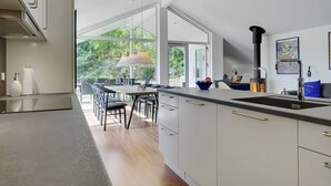 A modern kitchen with a large window, a dining area, and a stove. - "Rikkie" - 150m to the fjord by Interhome (Rørvig)