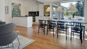 A modern kitchen with white cabinets, a black countertop, and a dining area with a wooden table and chairs. - "Rikkie" - 150m to the fjord by Interhome (Rørvig)