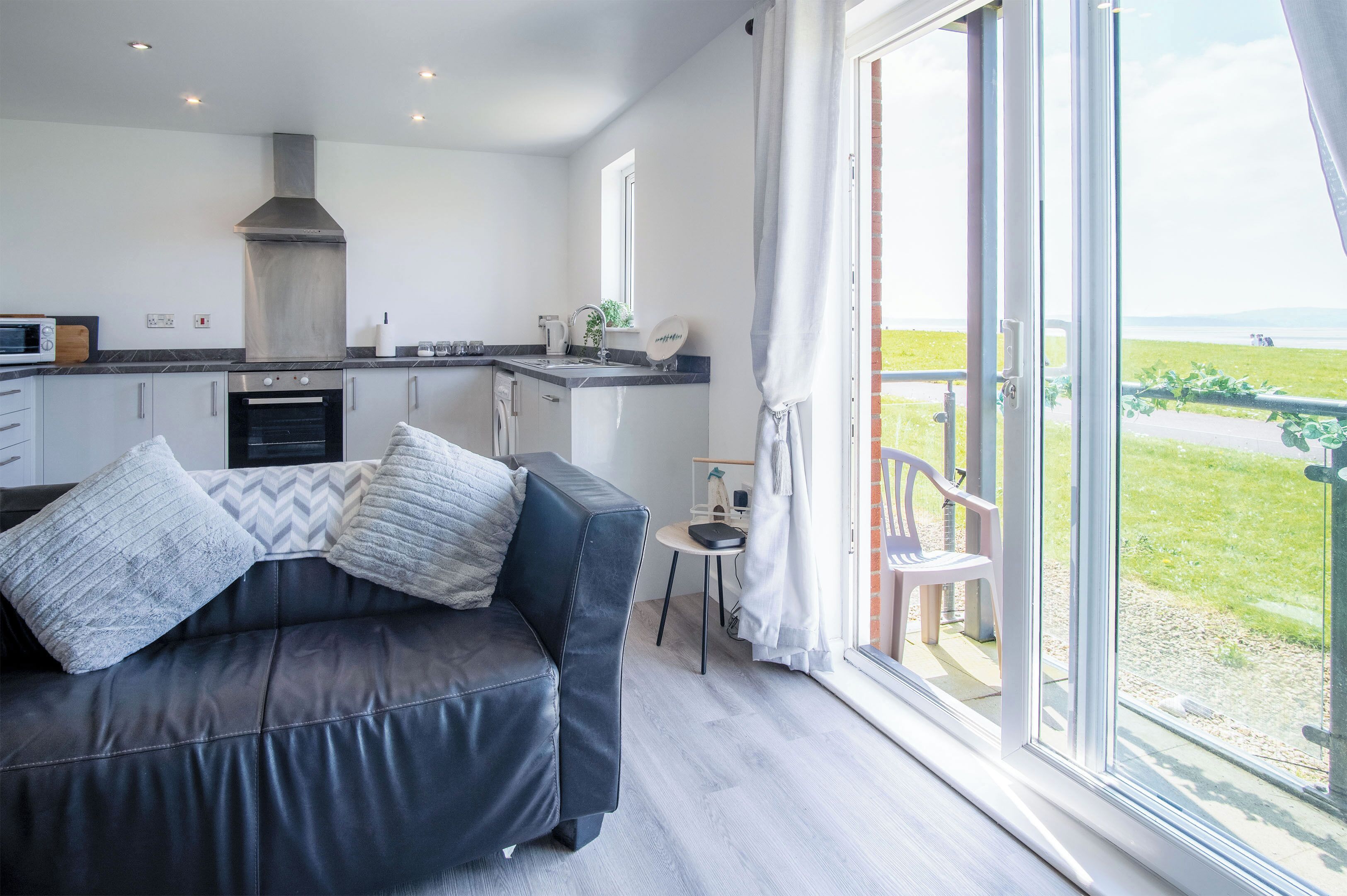 A modern kitchen with a built-in oven and a large window overlooking a grassy area.