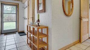 Un pasillo con un banco de madera, un espejo y una puerta.