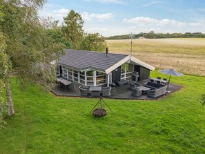 A modern house with a large deck, outdoor seating, and a swing chair.