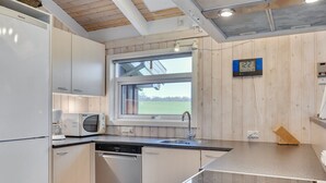 A modern kitchen with white cabinets, a microwave, a dishwasher, and a large window.