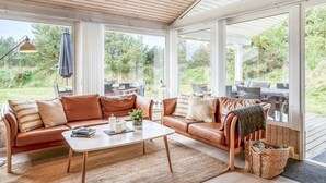 A spacious living area with a wooden ceiling and large windows, a leather sofa, a coffee table, and a view of the outdoors. - "Helene" - 1.5km from the sea by Interhome (Blokhus)