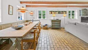 A kitchen with a wooden table, chairs, pendant lights, a bookshelf, and a television. - "Tatiane" - 10km from the sea by Interhome (Bækmarksbro)