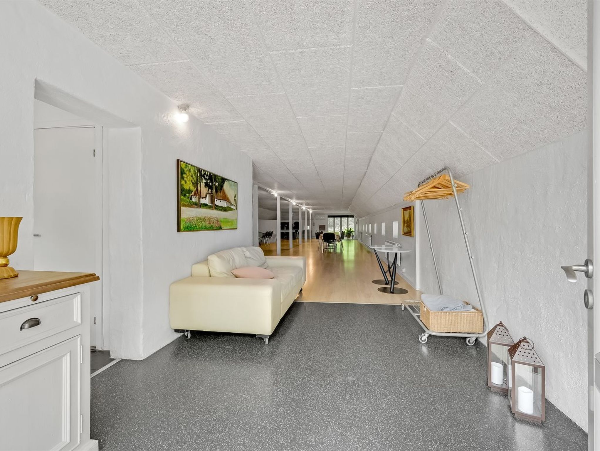 A spacious hotel room with a large bed, a desk with a lamp, a wardrobe, and a view of the hallway.
