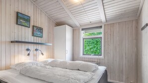 A bedroom with a bed, a window with a view of greenery, and wooden walls. - "Asko" - 350m from the sea by Interhome (Ebeltoft)