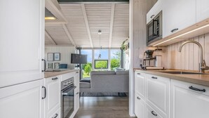 A modern kitchen with white cabinetry, a wooden countertop, and a built-in microwave. - "Asko" - 350m from the sea by Interhome (Ebeltoft)