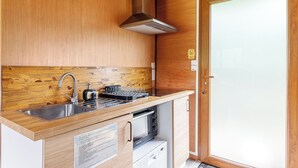 Cocina compacta con pileta de acero inoxidable, extractor y microondas.