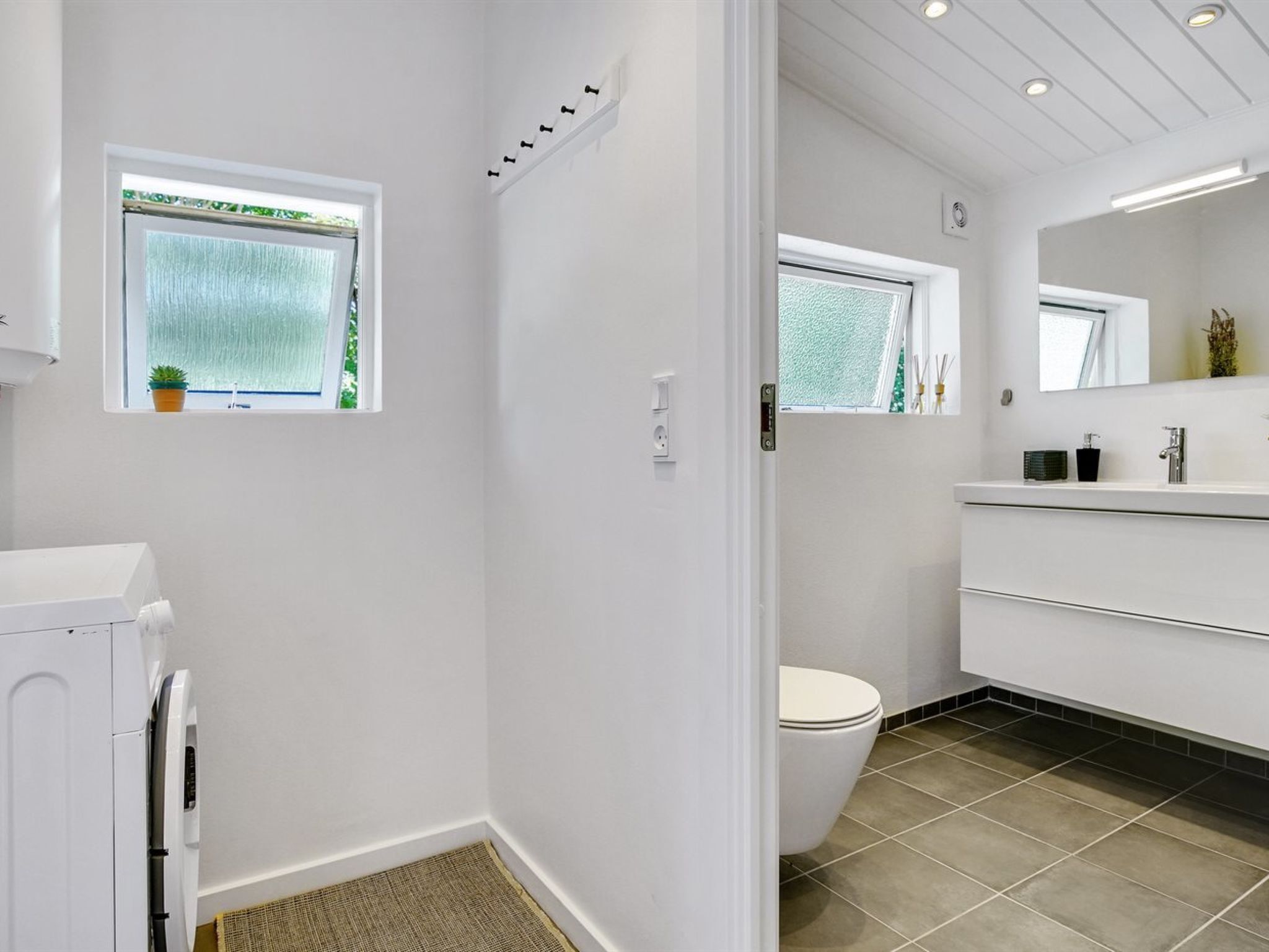 A modern bathroom with a toilet, a sink, and a window.