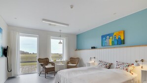 A bedroom with a large bed, two wicker chairs, a small table, and a painting on the wall. - "Martinus" - 5.5km from the sea by Interhome (Tim)