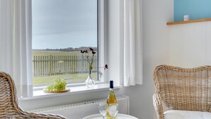 A room with a large window, wicker furniture, a small table with wine glasses, and a bottle. - "Martinus" - 5.5km from the sea by Interhome (Tim)