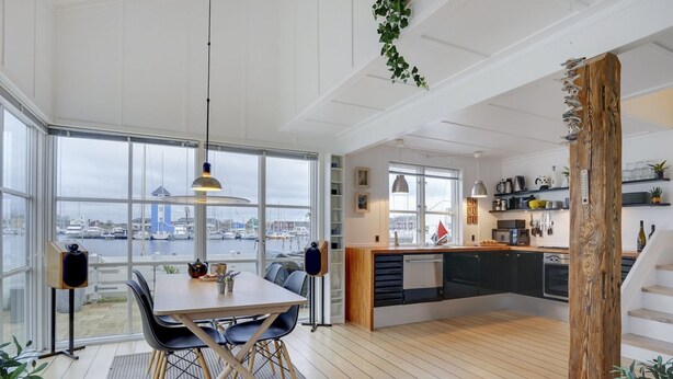 A modern kitchen with a view of the harbor, wooden flooring, and a dining area with a table and chairs.
