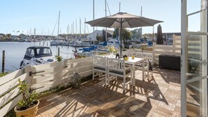 A patio with a table and chairs, overlooking a marina with boats.