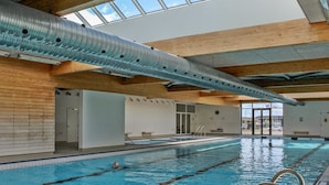 An indoor swimming pool with clear lanes, a wooden ceiling, and a skylight.