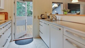 Een moderne keuken met witte kastjes, een houten aanrecht en een groot raam.