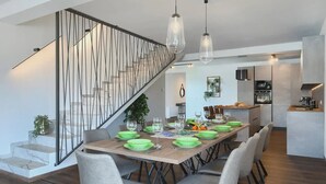 A modern dining area with a wooden table set for six, surrounded by six chairs. A staircase with a metal railing is visible to the left. - Artsi in Svetvin Enat (Svetvincenat)