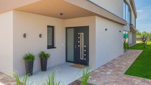 A modern building with a flat roof, a black door, and two potted plants on the ground floor. - Artsi in Svetvin Enat (Svetvincenat)
