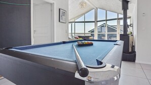 A pool table in a room with large windows, a ceiling fan, and a view of the outside.