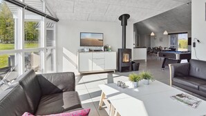 A spacious living area with a fireplace, a pool table, and a large window overlooking a garden.