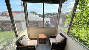 A covered porch with wicker furniture and a view of the neighborhood.