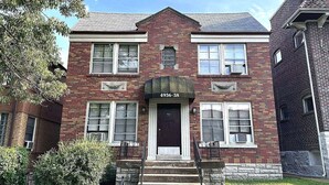A two-story brick building with a dark front door, numbered 4936-38, and a small porch with steps.