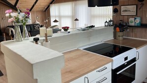 A modern kitchen with a wooden ceiling, a white countertop, a built-in stove, and a window with blinds. - "Thorgot" - 400m from the sea by Interhome (Sydals)