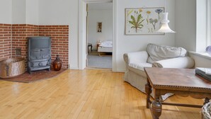 Un salon chaleureux avec une cheminée en briques, un canapé blanc et une table en bois.