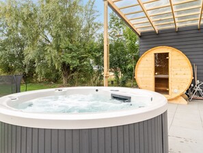 Un jacuzzi con revestimiento de madera y una sauna con paredes de vidrio.