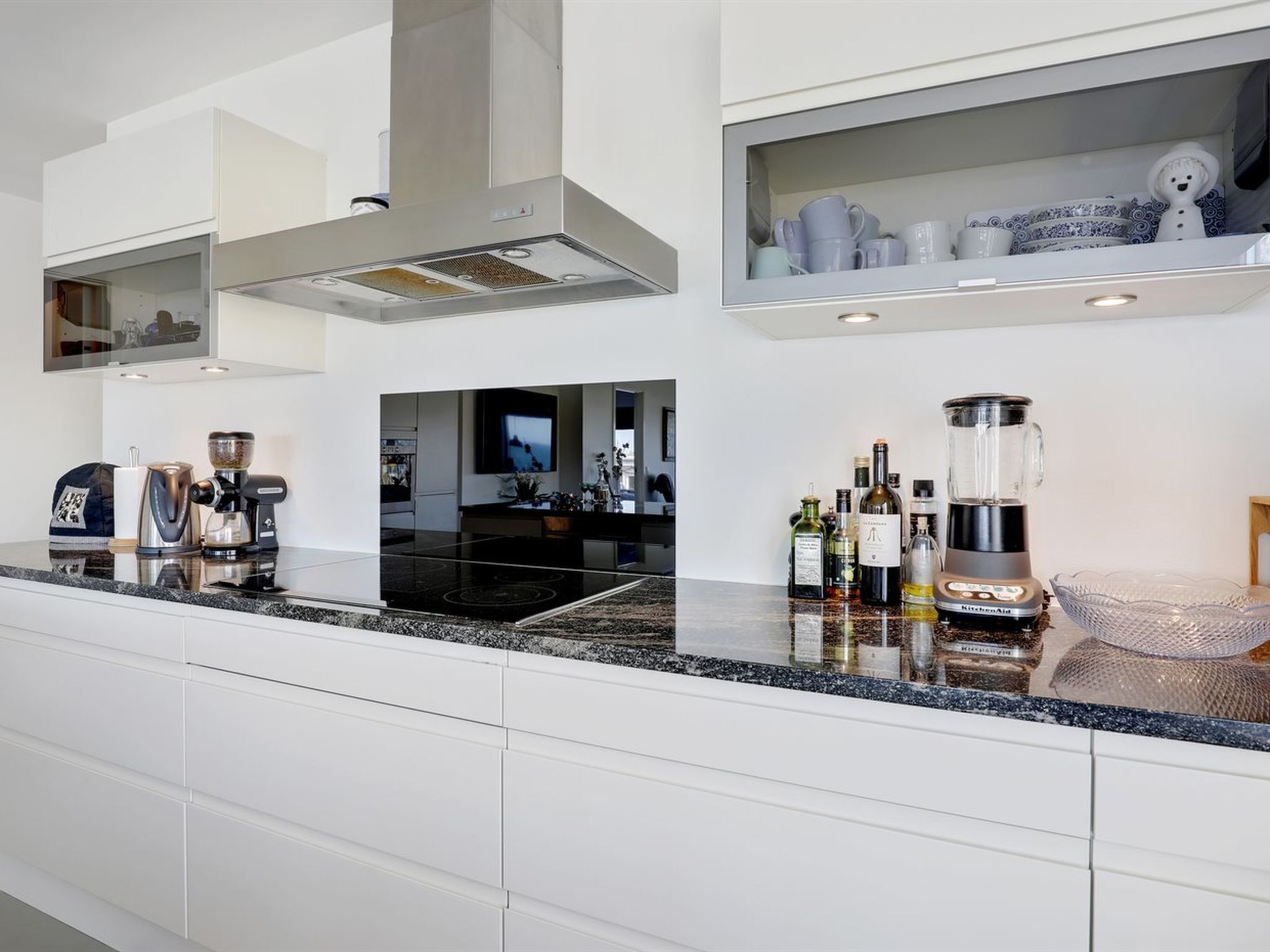 A modern kitchen with a black countertop, white cabinetry, and a built-in range hood.