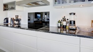 Een moderne keuken met een zwart aanrecht, witte kasten en een inbouw afzuigkap.
