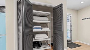 A walk-in closet with multiple shelves and a hanging rod, featuring a light blue cabinet to the left.