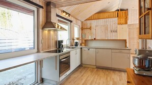 Une cuisine moderne avec des meubles en bois, un four encastré et une grande fenêtre.