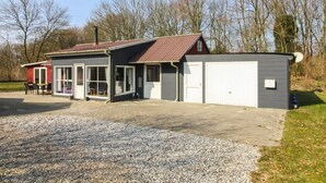 Un bâtiment à deux étages avec une allée en gravier et un petit garage attenant.