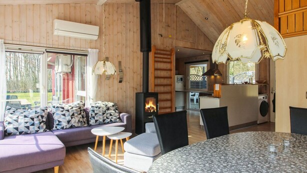 Un intérieur de chalet chaleureux avec un canapé, une table à manger et une cheminée.