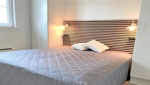 A bedroom with a bed, a headboard with horizontal slats, two bedside lamps, and a window. - "Eike" - 250m from the sea by Interhome (Brenderup Fyn)