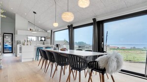 A modern kitchen with white cabinets, a central island, and a dining area with a large table and chairs. - "Gunborg" - 400m from the sea by Interhome (Sjølund)