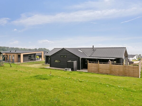 A modern house with a garage, a fenced yard, and a clear sky.