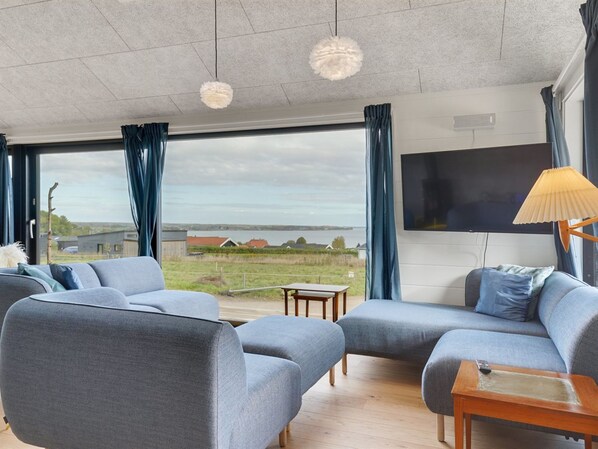 A modern living room with a large window, a flat-screen TV, and a wooden coffee table.