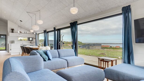 A modern living room with a large sofa, a dining area with a table and chairs, and a kitchen in the background. - "Gunborg" - 400m from the sea by Interhome (Sjølund)