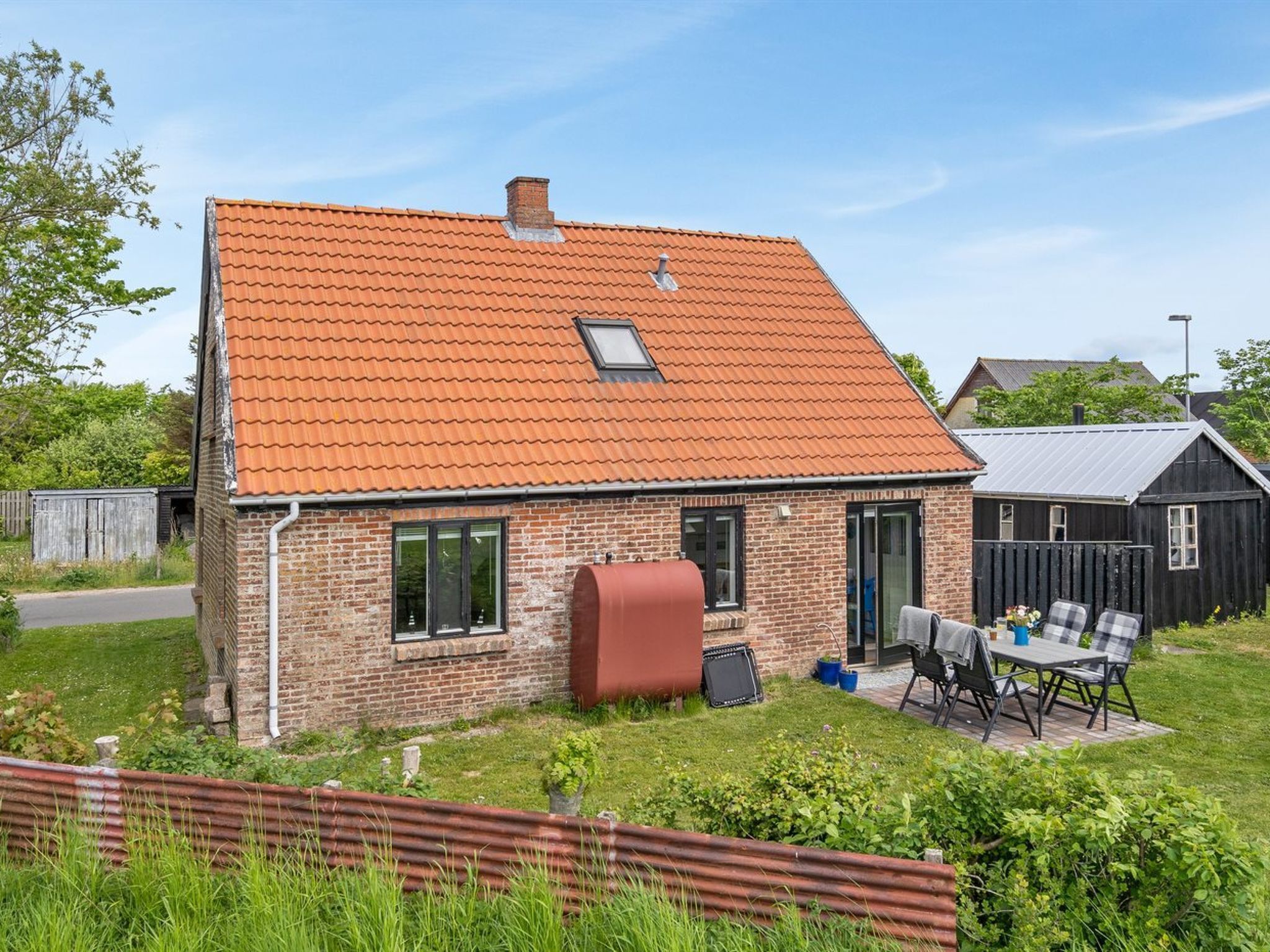 A two-story brick house with a red-tiled roof, a visible chimney, and a small attached garage.