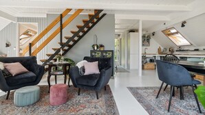 A modern loft with a staircase, a dining area, and a kitchen.
