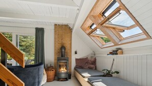 A cozy loft bedroom with a built-in wood-burning stove, a sofa, and a window seat.