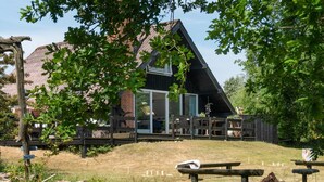 A rustic wooden house with a sloped roof, a glass door entrance, and a wooden deck.