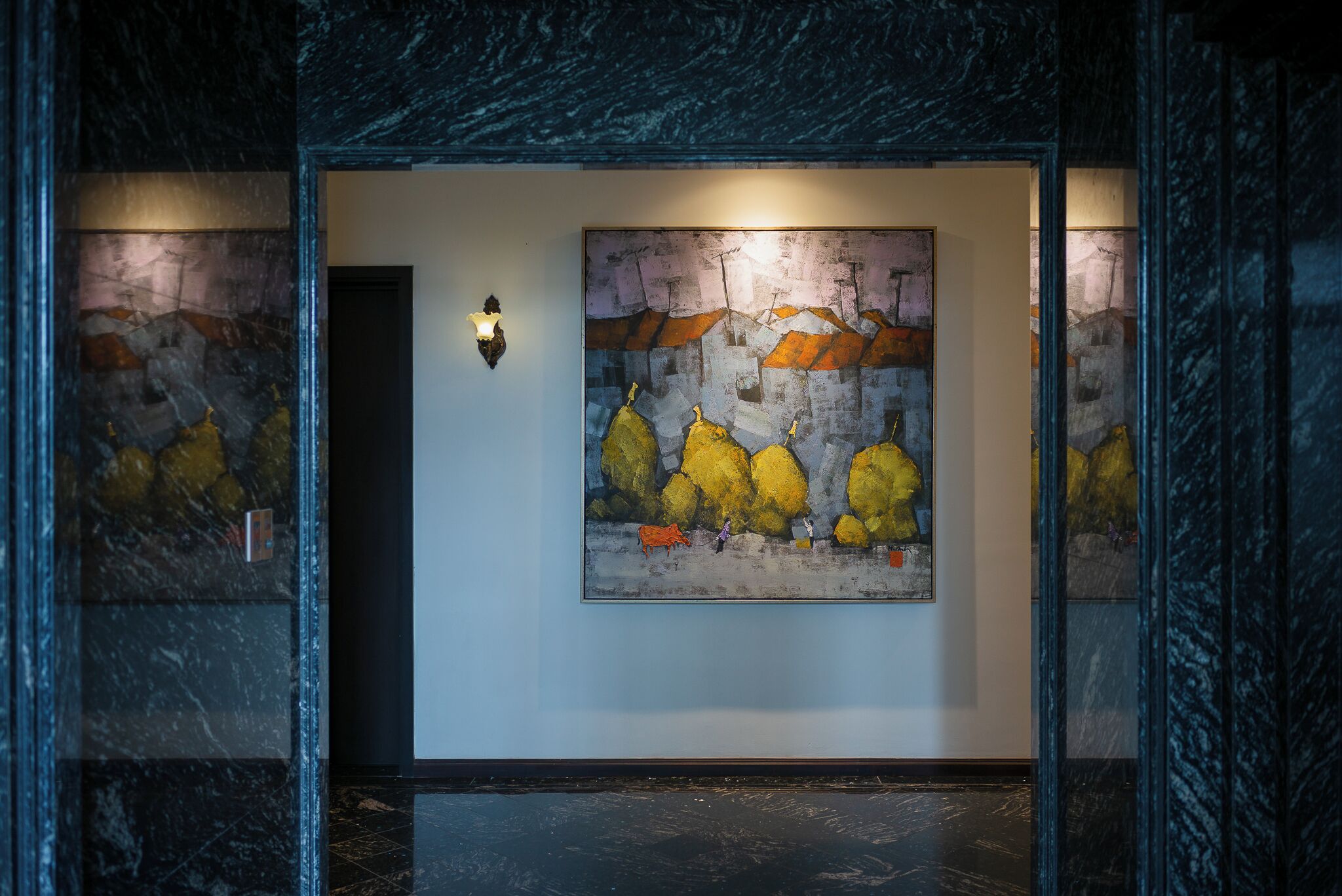 Un couloir avec une grande peinture abstraite au mur, un luminaire et un sol en marbre.