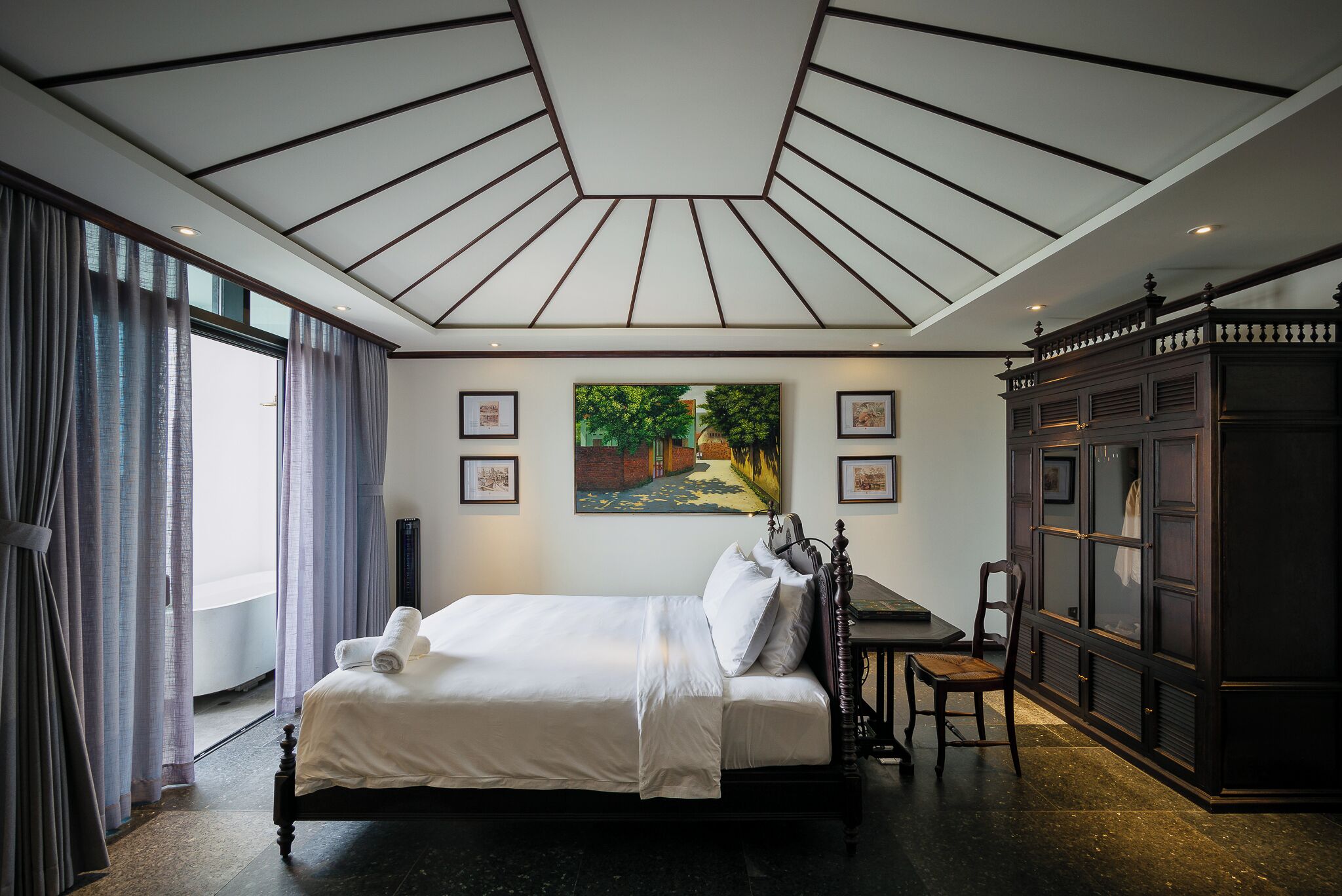 A neatly made bed with white linens, a painting on the wall, and a dark wooden cabinet.