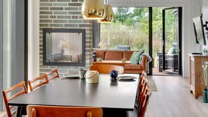 A dining area with a brick wall, a fireplace, and a large window overlooking a garden. - "Sinna" -  from the sea by Interhome (Hals)